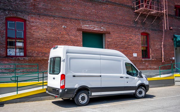 a white cargo van parked in front of an industrial brick building